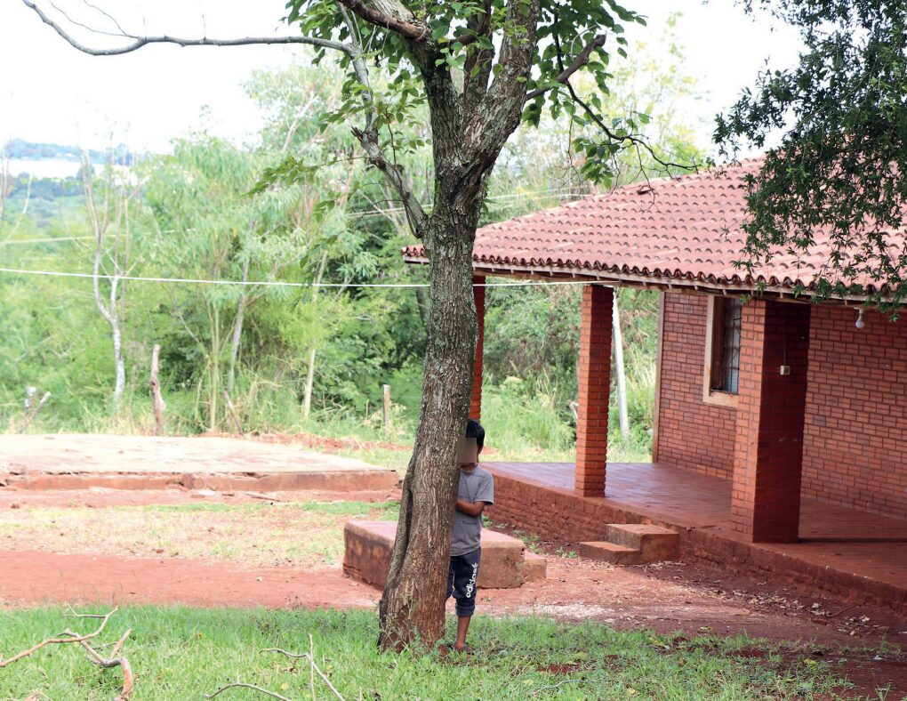 Niño escondido detrás de un árbol, en una escuela campesina del Paraguay.